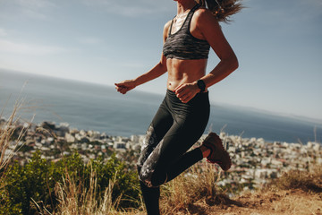 Healthy woman sprinting over mountain trail
