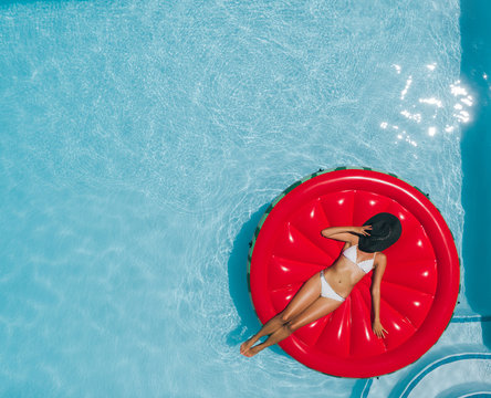 Woman sunbathing on floating mattress in swimming pool