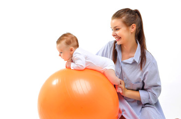 Mom and baby doing gymnastics on an orange fitball.