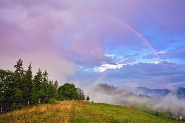 morning fog with red hot sunrise and rainbow in the mountains