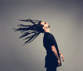 Young man flipping his dreadlocks back.