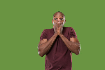 The young attractive man looking suprised isolated on green
