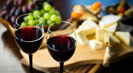 Pouring red wine into the glass in the background composition of appetizers
