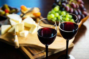 Pouring red wine into the glass in the background composition of appetizers