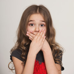 Shocked little girl covering her mouth by hands