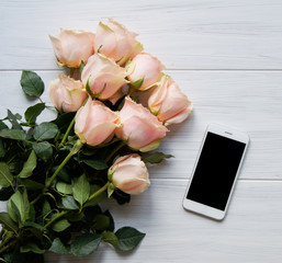 Flat lay stylish mock up photo with  phone and roses flowers on the wooden background. Feminine photo for blog and website. Mock up background for a product presentation.