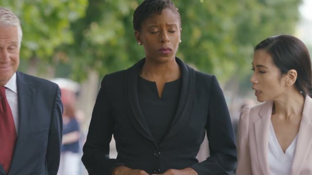 Group of 3 professionals walking and talking outside, in slow motion