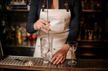 Female bartender mixing an ice in the glass