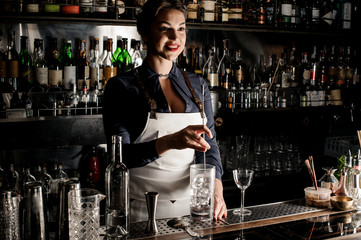 Female bartender stirring an alcoholic drink in the glass with ice