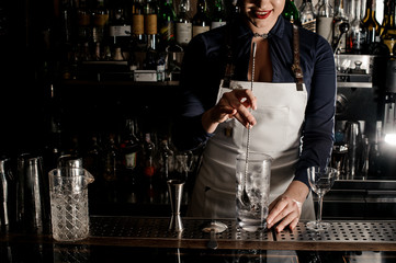 Attractive female bartender stirring an alcoholic drink in the glass