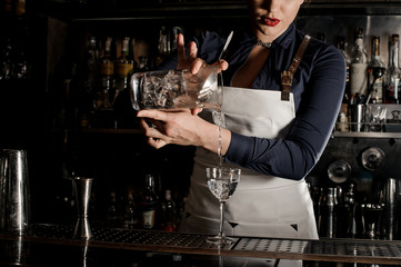 Bartender girl pouring an alcoholic drink from the measuring glass