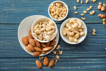 Bowls with different nuts on wooden background