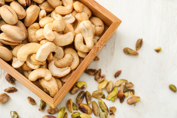 Box with different nuts on white wooden background