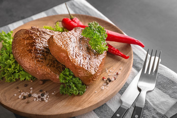 Plate with tasty steaks, herbs, chili and spices on grey table