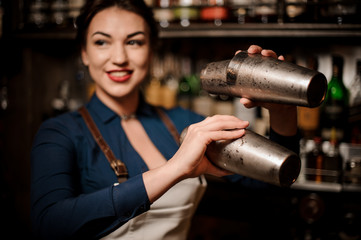 Bartender girl holding two steel cocktail shakers