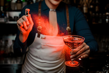 Bartender girl holding a delicious cocktail and spraying on it