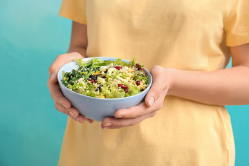 Woman holding bowl with tasty quinoa salad on color background