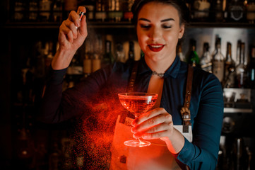Beautiful bartender girl spraying on the delicious cocktail in her hand