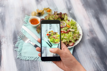 Woman taking photo of tasty quinoa salad with mobile phone
