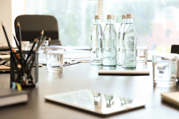 Table with bottles of water prepared for business meeting in conference hall