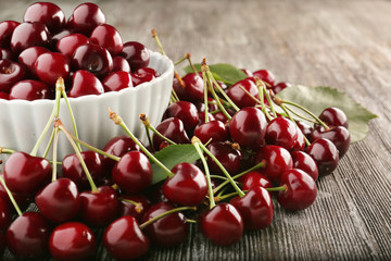 Bowl with tasty cherries on wooden table, closeup