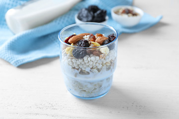 Tasty oatmeal dessert with almonds and dried fruits in glass on light background