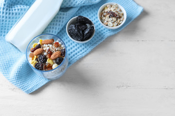 Tasty oatmeal dessert with almonds and dried fruits in glass on light background