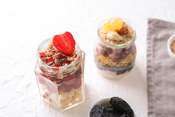Tasty oatmeal desserts in glass jars on light textured background