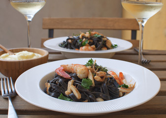 Seafood Squid ink pasta closeup Shrimp White wine Alioli Bamboo bowl Restaurant terrace Wooden table