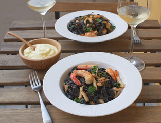 Seafood Squid ink pasta closeup Shrimp White wine Alioli Bamboo bowl Restaurant terrace Wooden table