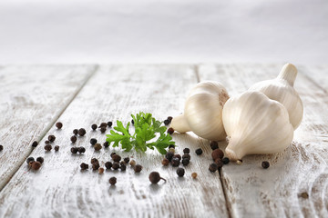 Fresh garlic with parsley and black pepper peas on white wooden table
