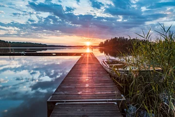 Foto op Aluminium Calm lake in sweden with a boat at the pier and a sunset over the horizon © LDJ - Photography