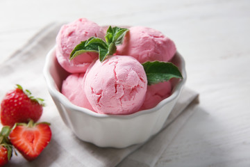 Bowl with delicious strawberry ice-cream on white wooden background