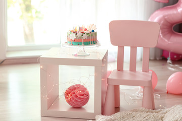 Stand with birthday cake on table in children room