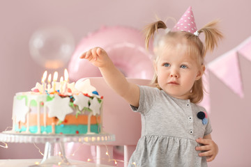 Cute little girl with birthday cake sitting on chair in room