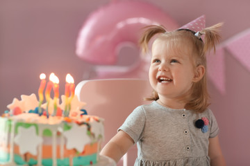 Obraz na płótnie Canvas Cute little girl with birthday cake sitting on chair in room