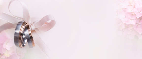Wedding rings on festive tender pink background