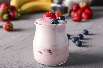 Glass jar with yogurt and fresh berries on table