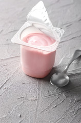 Plastic cup with yummy strawberry yogurt on grey textured background