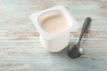 Plastic cup with yummy yogurt on wooden background