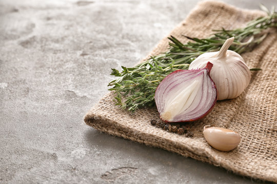 Fresh herbs with garlic and onion on grey textured background