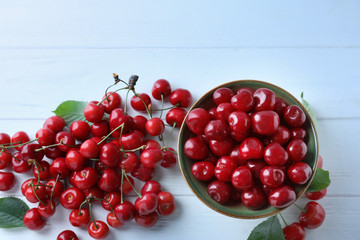 Bowl with tasty ripe cherries on wooden background