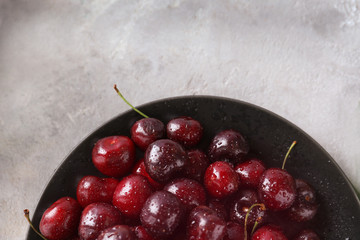 Bowl with tasty ripe cherries on grey background