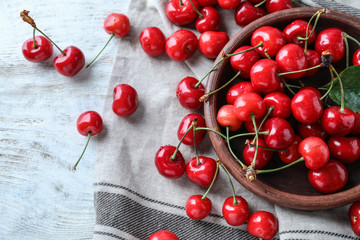Obraz na płótnie Canvas Bowl with tasty ripe cherries on white wooden background