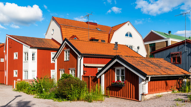 Historic alley with boatswain cabins and vintage houses in Vastervik, Sweden. The alley is covered in gravel. A small garden with flowers and herbs is situated outside the cabin.