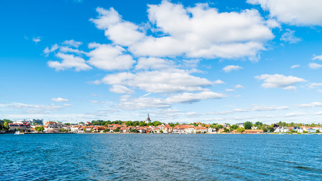 The coastal town of Vastervik, Sweden, on a sunny and fine summer morning. White clouds in the sky and a calm Baltic sea in the foreground. Logos removed.