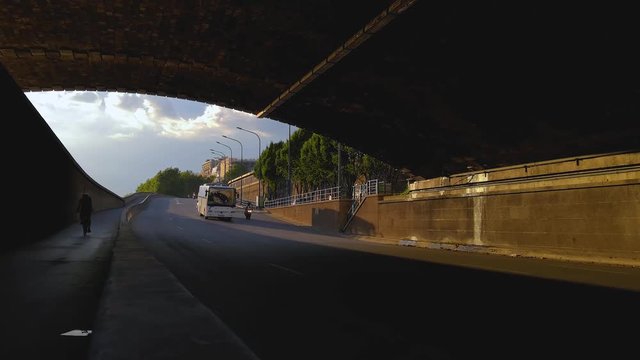 Traffic flowing through a tunnel next to the Seine in Paris, France during sunset. Motorbikes, scooters, taxi and different cars can be seen. On the left is a bike lane where a couple of bikes appear.