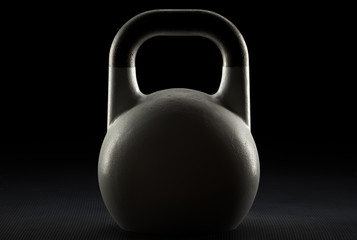 Backlit competition kettlebell silhouette on a fitness studio gym floor with potential copy space on kettlebell