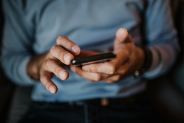 Close-up view of male hand holding smartphone. Blurred background.Blogger using mobile gadget. Horizontal.Colors profile