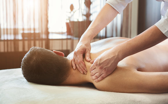 Massage therapist massaging male shoulders